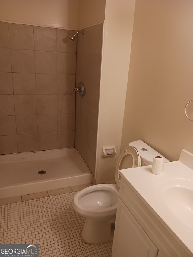 bathroom with vanity, toilet, a tile shower, and tile patterned flooring