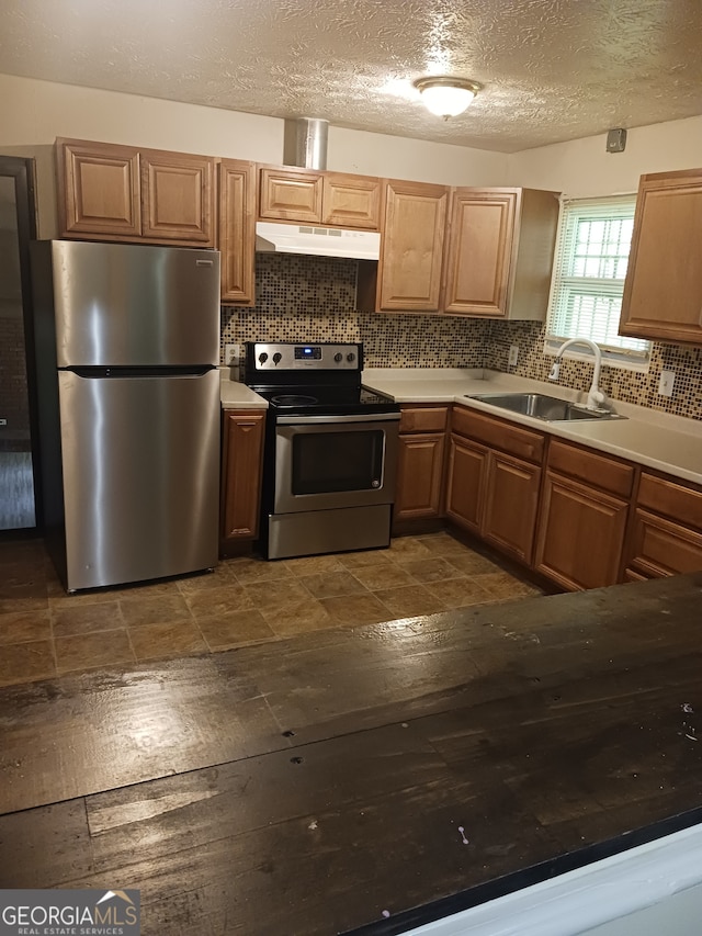 kitchen featuring sink, a textured ceiling, stainless steel appliances, and backsplash