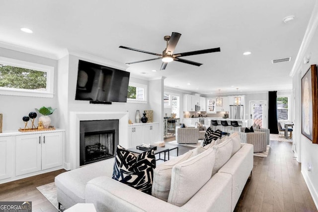 living room featuring hardwood / wood-style flooring, crown molding, and ceiling fan