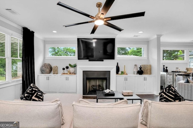 living room with crown molding, ceiling fan, and a healthy amount of sunlight