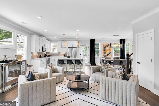 living room featuring an inviting chandelier, wood-type flooring, and ornamental molding