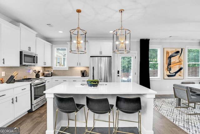 kitchen featuring appliances with stainless steel finishes, decorative backsplash, a kitchen island, and dark wood-type flooring