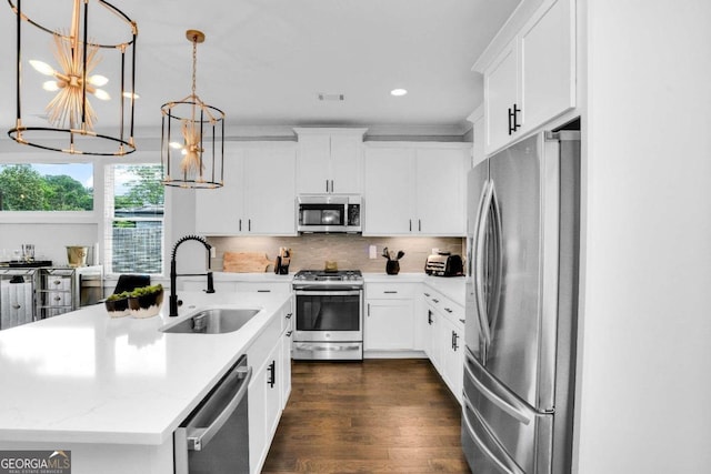 kitchen with appliances with stainless steel finishes, sink, backsplash, a kitchen island with sink, and dark wood-type flooring