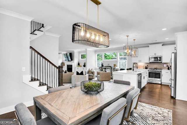 dining area featuring sink, dark hardwood / wood-style floors, a notable chandelier, and ornamental molding