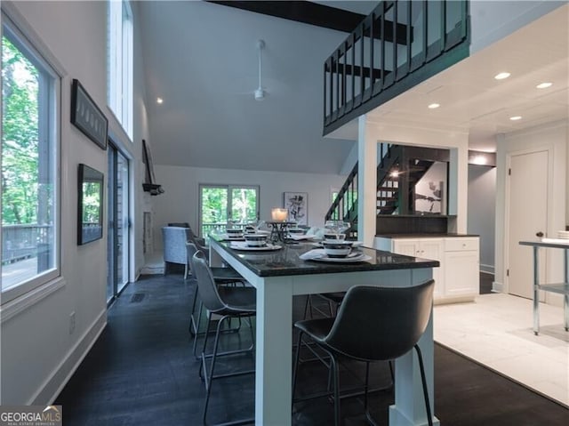 kitchen featuring hardwood / wood-style flooring, a high ceiling, white cabinets, a center island, and a kitchen bar