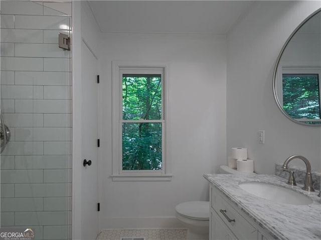 bathroom with tile patterned flooring, vanity, a tile shower, and toilet