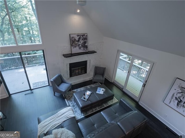 living room featuring a premium fireplace, vaulted ceiling, and dark hardwood / wood-style floors