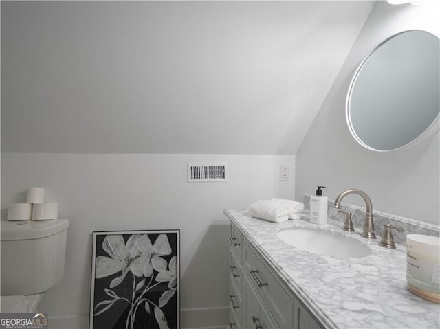 bathroom with vanity, vaulted ceiling, and toilet