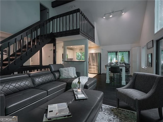 living room featuring track lighting, plenty of natural light, wood-type flooring, and a towering ceiling