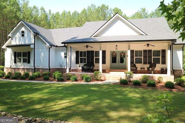 view of front of house featuring a ceiling fan, roof with shingles, a porch, board and batten siding, and a front yard