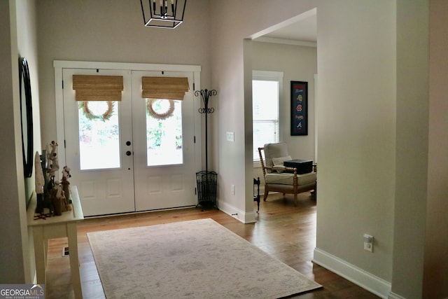 foyer with crown molding, french doors, wood finished floors, and baseboards