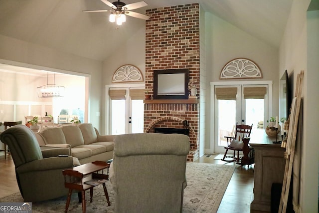 living area with high vaulted ceiling, french doors, a fireplace, and wood finished floors