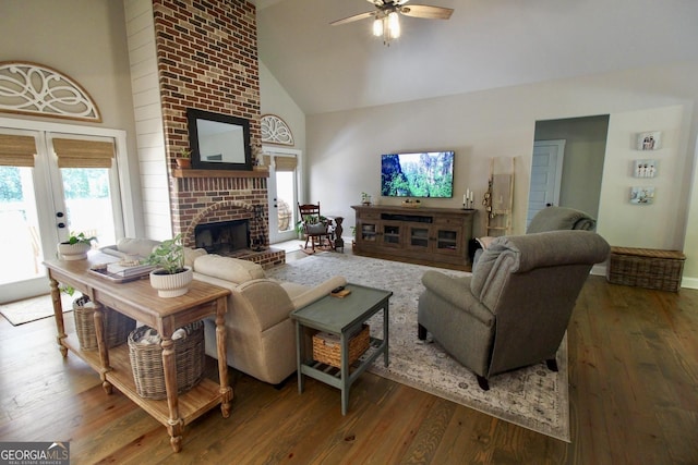 living room with ceiling fan, high vaulted ceiling, french doors, a brick fireplace, and wood-type flooring