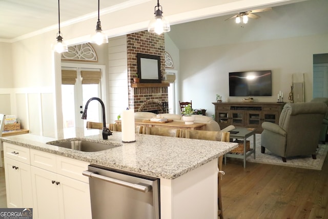 kitchen featuring dishwasher, open floor plan, a brick fireplace, pendant lighting, and a sink