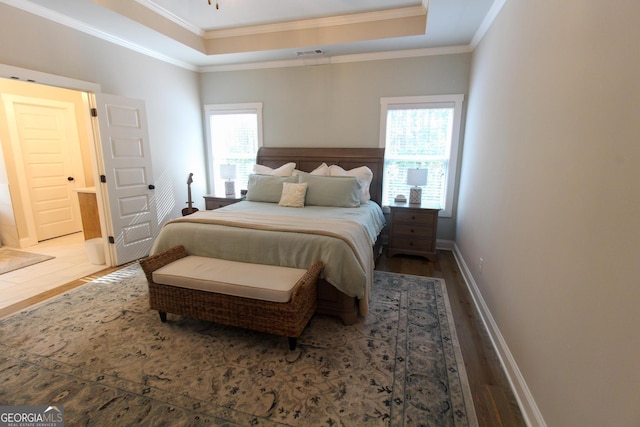 bedroom featuring visible vents, multiple windows, a tray ceiling, and wood finished floors