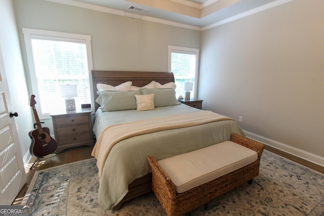 bedroom with dark wood-style floors, visible vents, ornamental molding, and baseboards