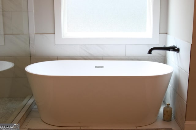 bathroom with a soaking tub, a healthy amount of sunlight, and tile patterned floors