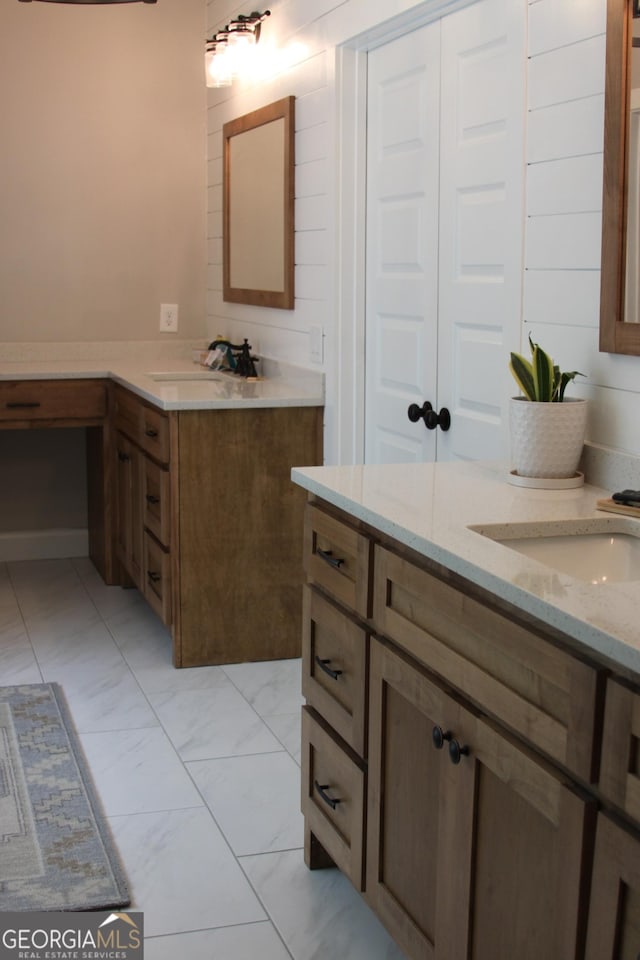 bathroom with marble finish floor, two vanities, and a sink