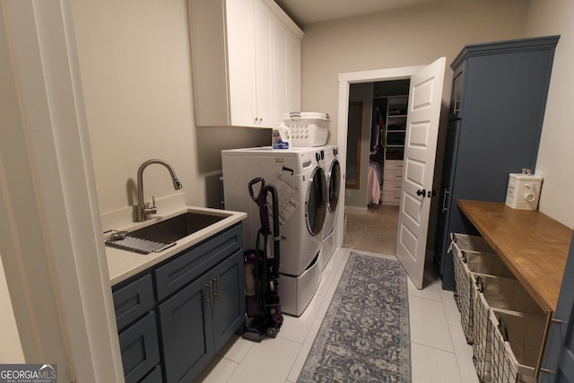 clothes washing area with cabinet space, a sink, washer and clothes dryer, and light tile patterned floors