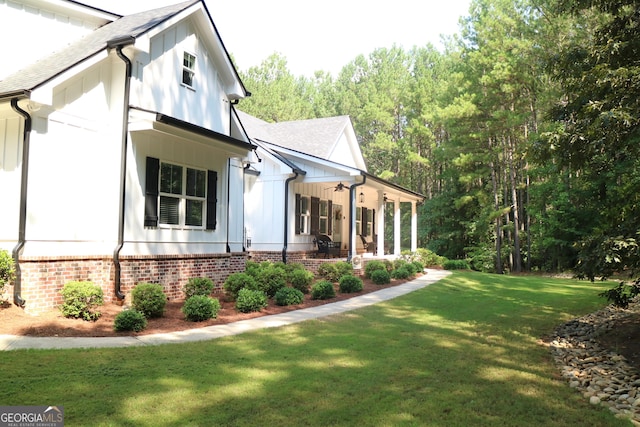 view of property exterior featuring board and batten siding, covered porch, roof with shingles, and a yard