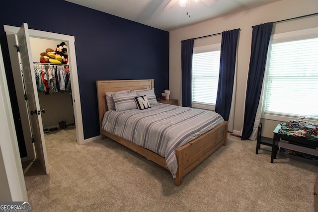 bedroom featuring light carpet, baseboards, ceiling fan, a spacious closet, and a closet