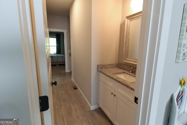 bathroom with baseboards, visible vents, wood finished floors, ensuite bathroom, and vanity