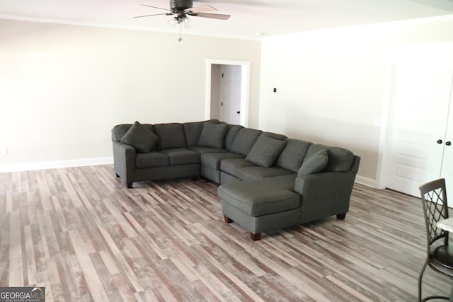 living area with a ceiling fan, crown molding, light wood-style flooring, and baseboards