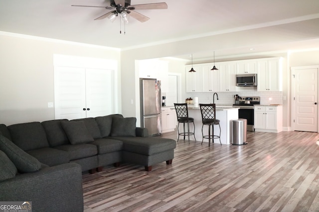 living area featuring ornamental molding, ceiling fan, and wood finished floors