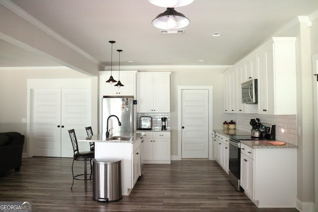 kitchen featuring a center island with sink, white cabinetry, stainless steel appliances, and decorative light fixtures