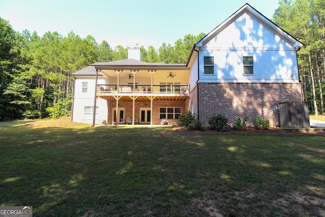 back of property featuring a chimney, a lawn, a ceiling fan, and brick siding