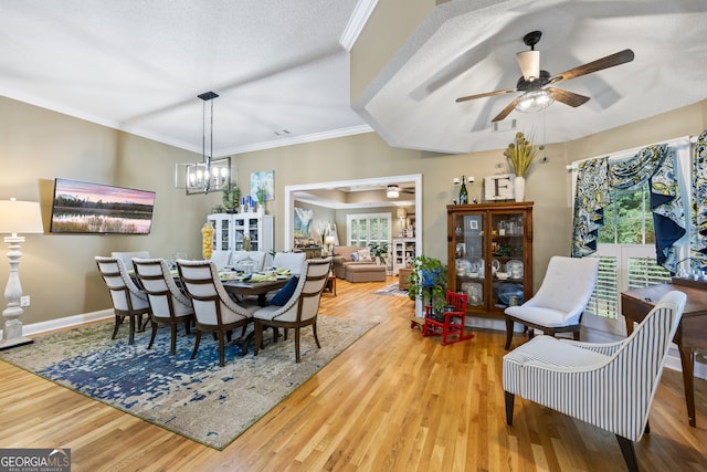 dining area with ornamental molding, ceiling fan with notable chandelier, a healthy amount of sunlight, and wood finished floors