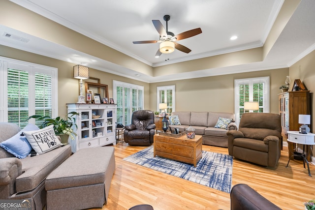 living room with plenty of natural light, crown molding, visible vents, and wood finished floors