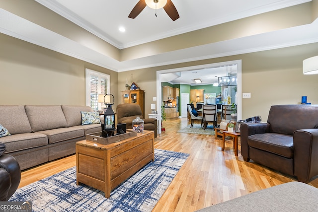 living room featuring light wood finished floors, recessed lighting, ornamental molding, and ceiling fan with notable chandelier