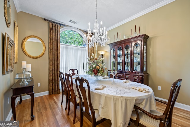 dining area featuring baseboards, crown molding, visible vents, and wood finished floors