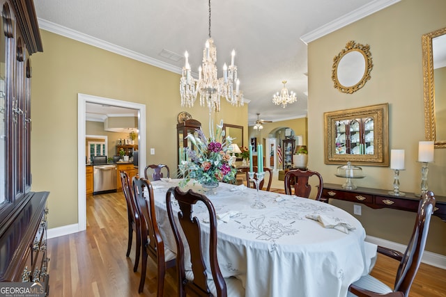 dining space featuring ceiling fan with notable chandelier, baseboards, wood finished floors, and crown molding