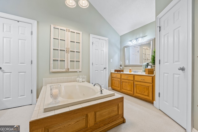 full bath featuring vaulted ceiling, a tub with jets, a textured ceiling, and vanity