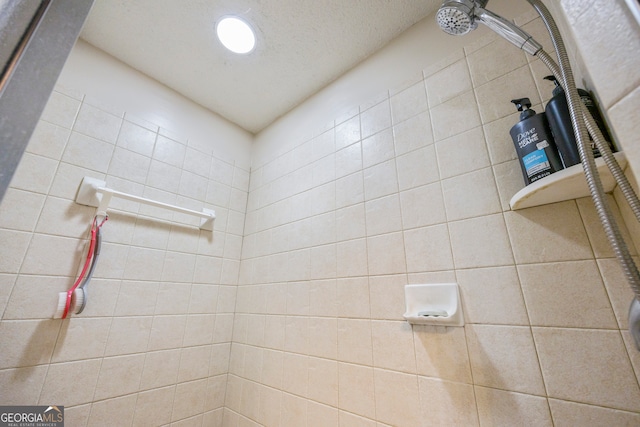 bathroom featuring a textured ceiling and tiled shower