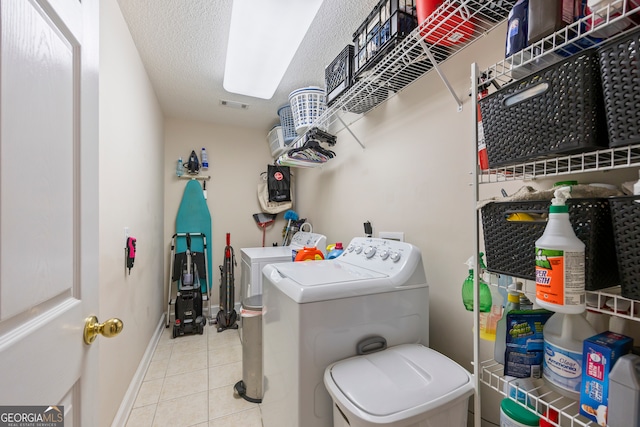 clothes washing area with a textured ceiling, tile patterned flooring, laundry area, baseboards, and washer and clothes dryer