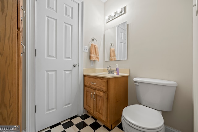 half bath featuring toilet, vanity, and tile patterned floors