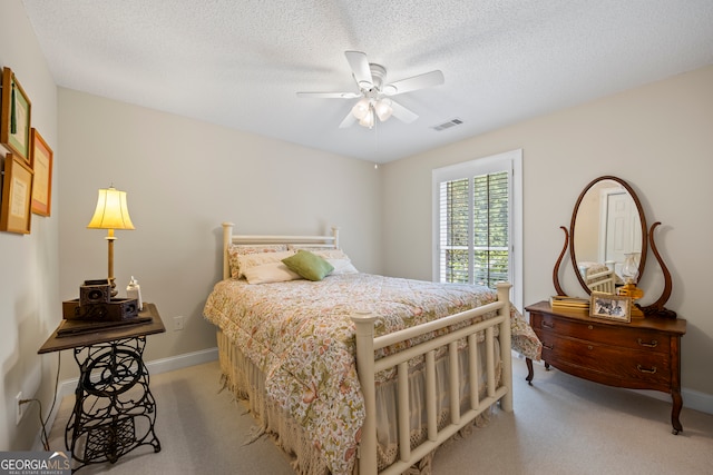 bedroom featuring light colored carpet, visible vents, and a textured ceiling