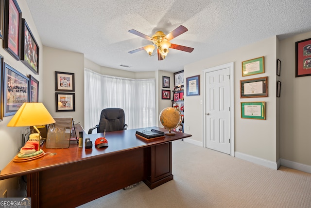 home office with a textured ceiling, carpet, a ceiling fan, and baseboards