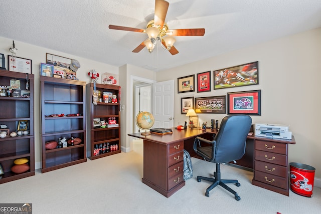 home office with a ceiling fan, carpet flooring, and a textured ceiling