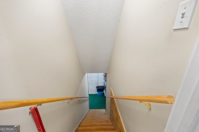 stairway with lofted ceiling and wood finished floors