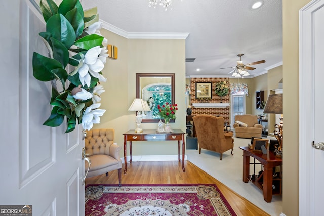 foyer featuring a textured ceiling, wood finished floors, a ceiling fan, baseboards, and crown molding