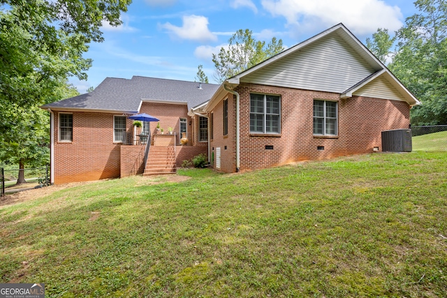 back of property with crawl space, fence, a yard, central air condition unit, and brick siding