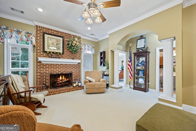 living area with a fireplace, crown molding, and ornate columns