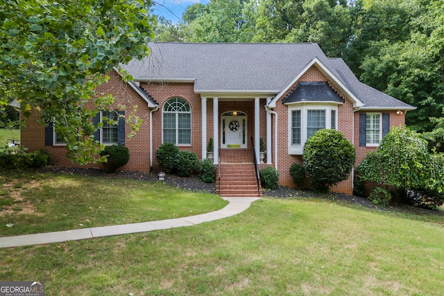 view of front of home featuring roof with shingles, a front lawn, and brick siding