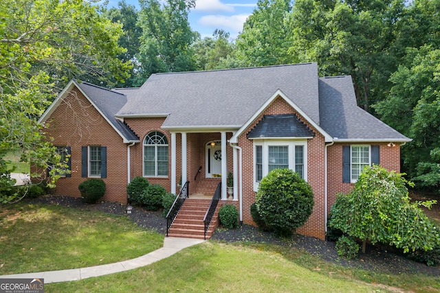 view of front facade with a shingled roof, brick siding, and a front lawn