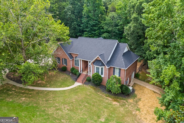 view of front of house with a garage, roof with shingles, a front lawn, and brick siding