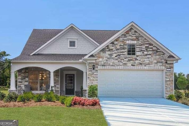 craftsman-style house featuring a garage, covered porch, and a front lawn